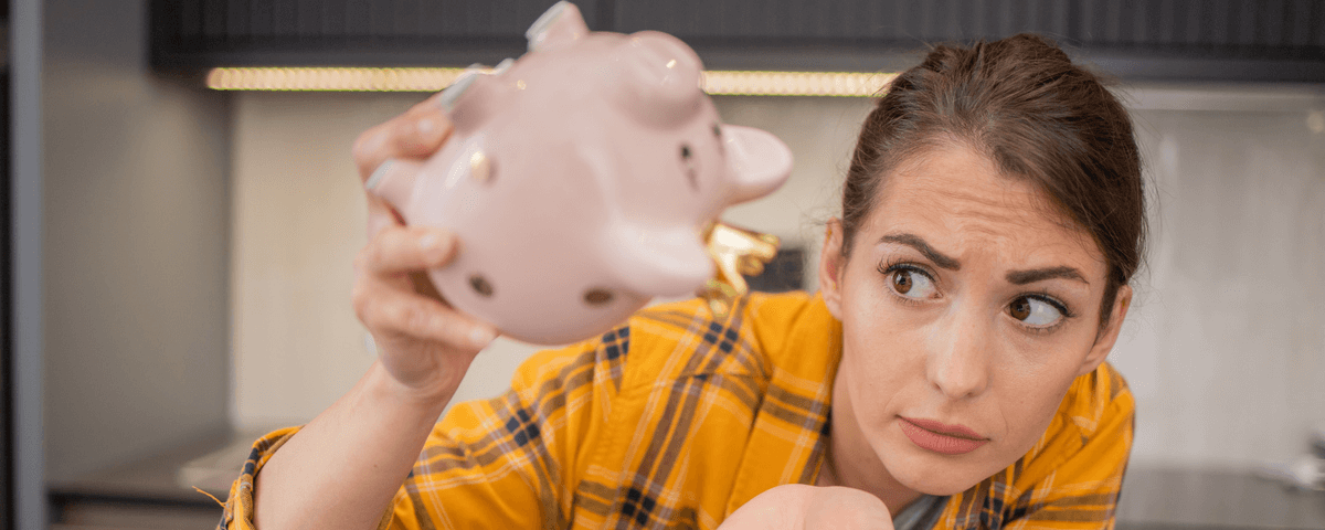 Une jeune femme stressée tient sa tirelire tout en économisant de l'argent.